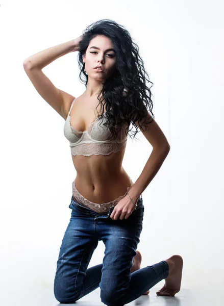 Mujer sexy seductora. Modelo de moda deseable. Chica sexy erótica. Ajuste y sexy. Una seductora rizada. Mujer caliente desnudándose. Mujer largo rizado peinado desgaste encaje lencería quitándose pantalones vaqueros denim —  Fotos de Stock