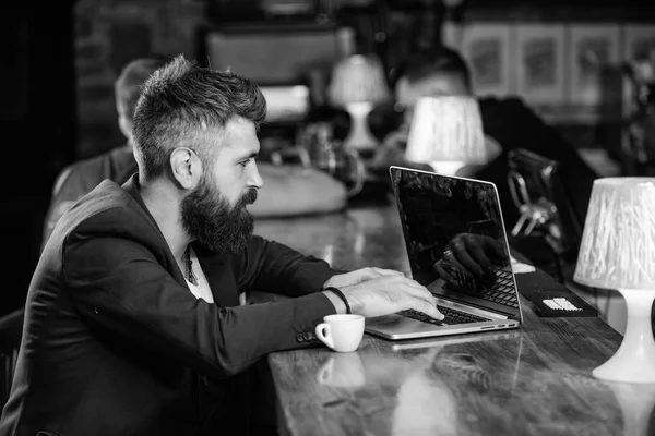 Koffiepauze concept. Man met baard zakenman sit bar teller met laptop en kopje koffie. Blog van het web van de inhoud maken Manager maken post genieten van koffie. Hipster freelancer werk online drinken koffie — Stockfoto