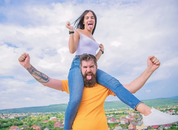 Having some chemistry. Hipster giving sexy woman a piggyback ride. Happy couple in love on cloudy sky. Loving couple happy smile having fun. Bearded man piggybacking his girlfriend just for fun
