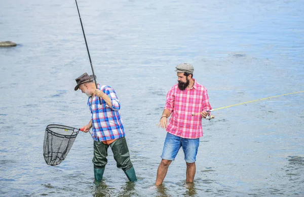 L'amicizia maschile. Padre e figlio pescano. Weekend estivo. Pesca insieme. Gli uomini sono in acqua. La pesca è molto più del pesce. Buon pescatore con canna da pesca e rete. Hobby e attività sportive — Foto Stock