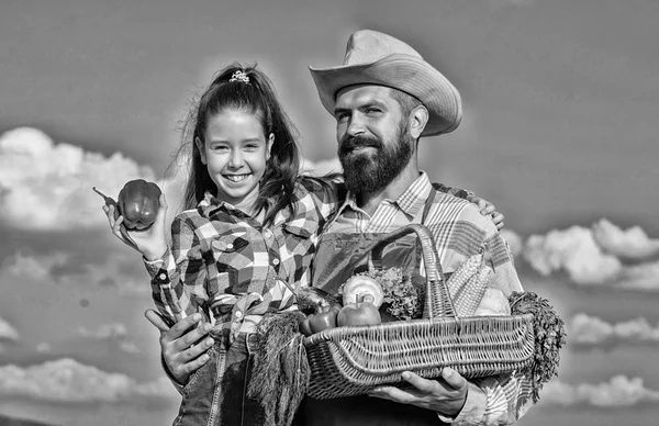 Family farm concept. Only organic and fresh harvest. Man bearded rustic farmer with kid. Farmer family homegrown harvest. Father and daughter hold basket harvest vegetables. Gardening and harvesting