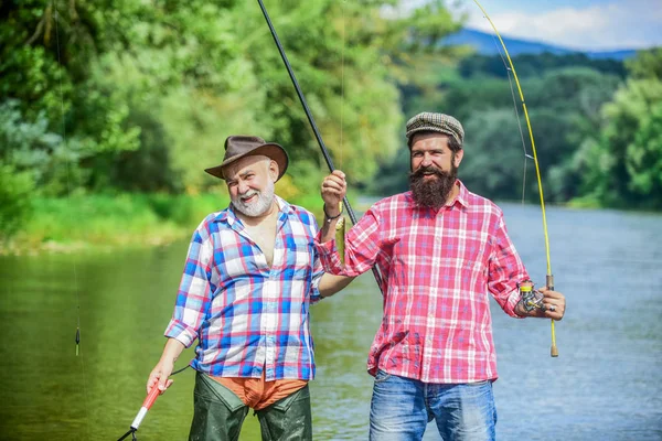 ひげを生やした男が魚を捕まえる友人釣りを持つ成熟した男。夏休み。幸せな陽気な人々。家族の時間だ釣り竿を持つ漁師。活動と趣味。釣り淡水湖池川 — ストック写真