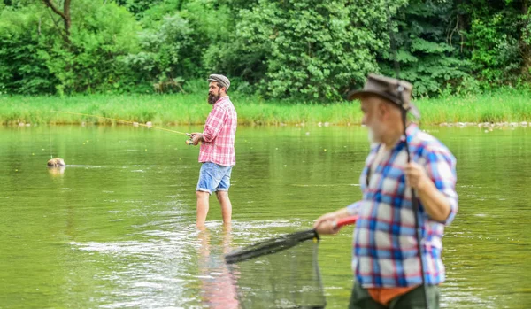 Competitors. male friendship. family bonding. summer weekend. two fishermen with fishing rods, selective focus. mature man fisher. hobby and sport activity. son and father fishing — Stock Photo, Image