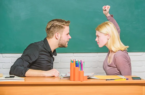 Conflict situation. Teacher and schoolmaster are at quarrel. Angry woman going to man with her fists. Couple arguing in classroom. University or college students back to school. High school education — Stock Photo, Image