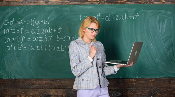 Senhora professora usar óculos detém laptop surf internet. Professor mulher loira com laptop moderno surf internet chalkboard fundo. Inovação escolar. Conceito de educação à distância — Fotografia de Stock