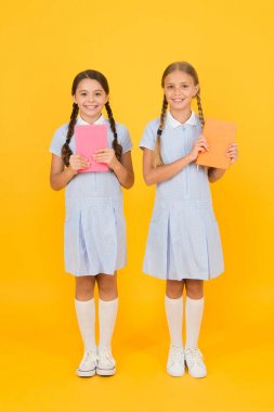 Okullar için eğitim kitapları. Kitap okuyorum. Okul kütüphanesi. Evde eğitim konsepti. Okuryazarlık kulübü. Sarı arka plan üzerine kitaplar tutan sevimli çocuklar. Ansiklopedi veya çocuk kitapları ile küçük kızlar