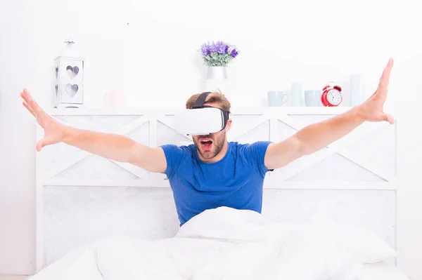 Stepping into the future. Handsome man wearing virtual reality headset in bed. Future vision. The future of entertainment and communication. Future concept