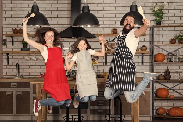 Morning cooking. Family day. Father, mother and child chef cooking. Mother and father with little girl. Happy family in kitchen. Little girl with parents in apron. Bearded man happy woman with kid