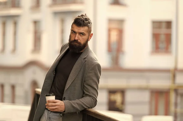 The best time of day to drink coffee. Hipster with reusable paper cup walking in city. Bearded man enjoying morning coffee. Businessman in hipster style holding takeaway coffee. Coffee drinker