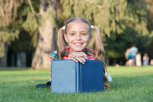 Schulzeit. Entwicklung fürsorglicher Lernender, die aktiv wachsen und Erfolg haben. Kleines Kind liest Buch. liebenswerter Bücherwurm. Schulmädchen lesen Geschichten entspannt grünen Rasen. Netter Schüler liest gern — Stockfoto