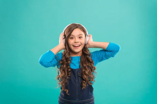 Νιώθοντας την ομορφιά του τραγουδιού. Χαριτωμένο μικρό παιδί ακούγοντας το τραγούδι σε μπλε φόντο. Αξιολάτρευτο κοριτσάκι απολαμβάνει το τραγούδι παίζοντας με τα ακουστικά. Σύνθεση τραγουδιού — Φωτογραφία Αρχείου