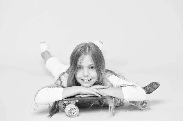 滑板创造了时髦。可爱的小溜冰者微笑着与时髦的风格和外观。可爱的小嬉皮士放松在粉红色背景的滑板。快乐嬉皮士与紫便士板 — 图库照片