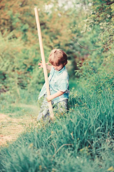 Kisfiú lapátot keres kincseket. Boldog gyermekkorban. Kaland vadászat kincseket. Kis segítő dolgozik a kertben. Aranyos gyermek a természetben szórakozik a lapátot. Szeretnék kincseket találni — Stock Fotó