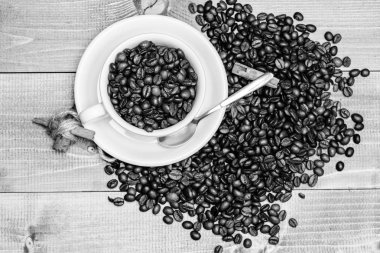 Kafein konsepti. İlham ve enerji yükü. Fincan tam kahve kahverengi kavrulmuş fasulye mavi ahşap arka plan. Kahve dükkanı konsepti. Cafe içecekler menüsü. Kahve molası verin ve rahatlayın. Taze kavrulmuş kahve çekirdekleri