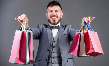Alışverişten hoşukolan pozitif adam. papyonda iş adamı. alışveriş çantaları ile şık bir esthete. tatil satın alma. Iş. Büyük satış. ağır çantalar. Olgun alışverişkolik. resmi takım elbiseli sakallı adam