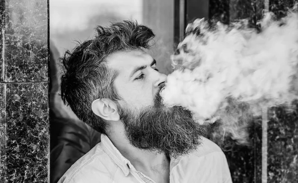 Fumar cigarrillo electrónico. Concepto de alivio del estrés. Dispositivo de fumar. Hombre barba larga relajado con hábito de fumar. Nubes de humo aromatizado. Hombre barbudo fumando vapor. El hombre con barba exhala humo — Foto de Stock