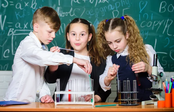 試験管を持つグループスクールの生徒は、化学液体を研究します。学校の研究室液体を実験する女の子と少年。カラフルな液体物質を含む試験管。液体状態に関する研究 — ストック写真