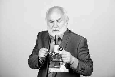 Mikroskoplu olgun adam resmi takım elbisesi. Doktora ve doktora sonrası istihdam. Moleküler biyoloji doktora projeleri. Biyoloji deneyimli öğretim görevlisi. Profesör üniversite öğretim üyesi. Bilim adamı mikrobiyolojisi