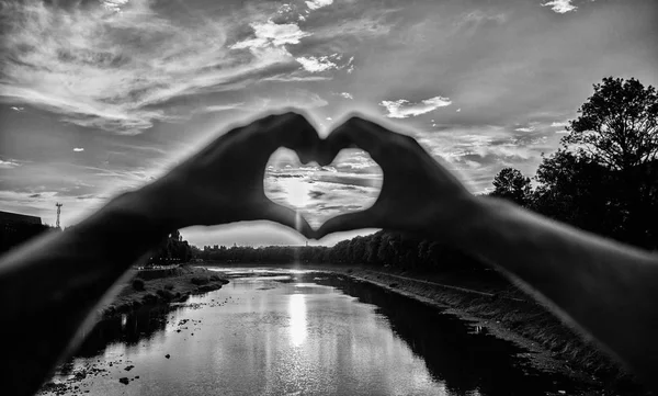 Summer memories concept. Top places for romantic date. Sunset sunlight romantic atmosphere. Male hands in heart shape gesture symbol of love and romance. Heart gesture in front of sunset above river