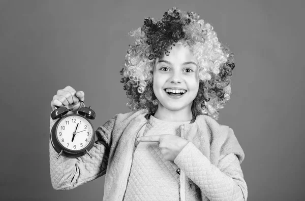 私は規律について冗談を言っていません。誤報だ女の子は時間を心配します。楽しむ時間だ規律と時間の概念。サーカス公演のタイミング。子供カラフルな巻きかつらピエロスタイルは、目覚まし時計を保持します — ストック写真