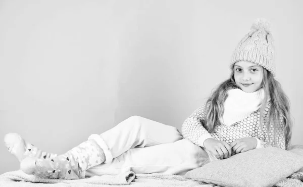 Χειμερινή μόδα για τα παιδιά. Μοντέλο μόδας χαμογελαστό παιδί. Χειμερινή μόδα έννοια. Παιδί κορίτσι φορούν χαριτωμένο πλεκτό καπέλο μοντέρνα και άνετα ζεστά ρούχα. Το κορίτσι χαλάρωση ροζ φόντο μακριά μαλλιά — Φωτογραφία Αρχείου