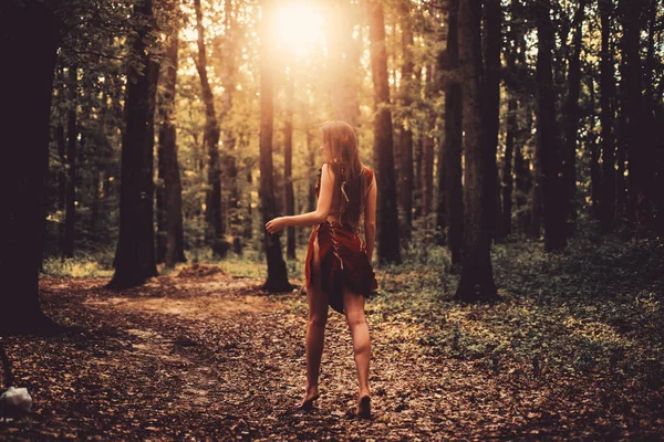 アマゾンの女性。セクシーな魔女革のスエードの服でセクシーな女の子。民族部族のファッション。深い森。クーガー女性。森の中の野生の女性。太陽の光を通して女性のシルエット。セクシーな若い女性 — ストック写真