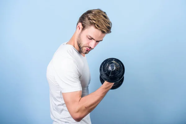 Sport lifestyle. Sport motivation. Handsome guy workout. Exercising at gym. Muscular man exercising with dumbbell. Sportsman training strong muscles. Sport equipment. Fitness and bodybuilding sport
