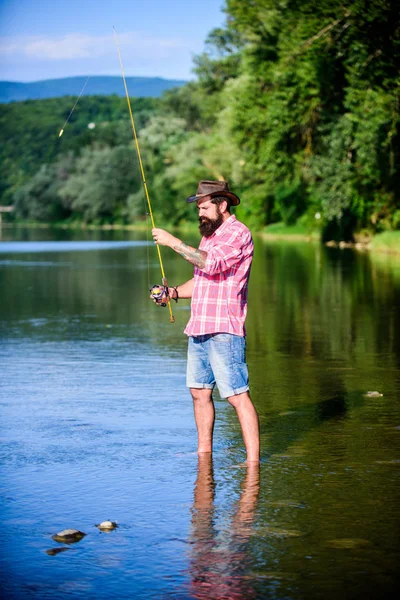 Отбрасываю. взрослый бородатый мужчина с рыбой на удочке. успешный рыбак в озерной воде. хипстерская рыбалка с ложкой-приманкой. Хобби для мух. Летняя рыбалка. Большая рыбалка. расслабиться на природе — стоковое фото