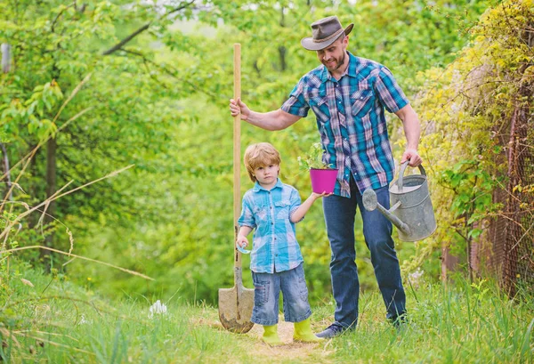 happy earth day. Family tree nursering. Eco farm. small boy child help father in farming. watering can, pot and shovel. Garden equipment. father and son in cowboy hat on ranch. Fond of horticulture