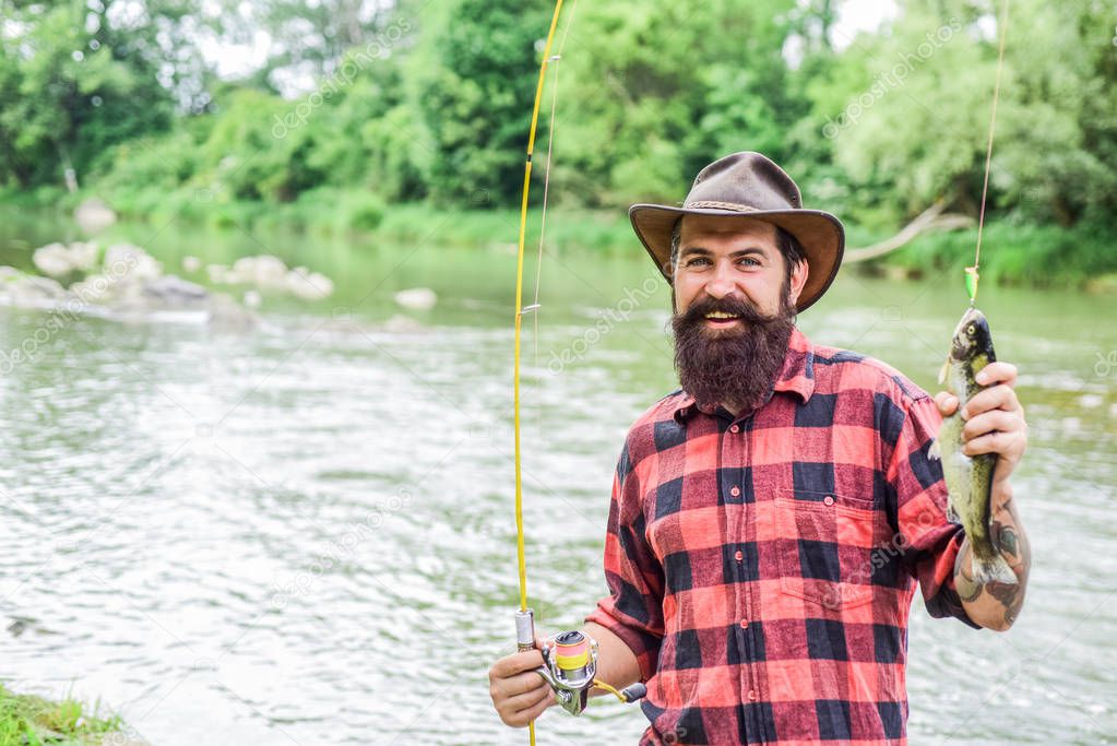 Fisher fishing equipment. Rest and recreation. Fish on hook. Brutal man stand in river water. Man bearded fisher. Fisher masculine hobby. Fishing requires to be mindful and fully present in moment