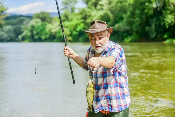 Pescatore con canna da pesca. Attività e hobby. Pesca d'acqua dolce lago stagno fiume. Non è sport, è ossessione. Uomo anziano barbuto cattura pesce. Uomo maturo che pesca. Pescatore barbuto in pensione — Foto Stock