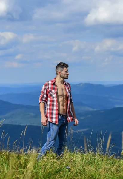 Yürüyüş konsepti. Doğanın gücü. Adam unbuttoned gömlek standı üst dağ manzara arka plan. Kaslı turist dağ tepeyürümek. Güçlü yürüyüşçü kas gövde. Atlet kaslı adam dağlar dinlenmek