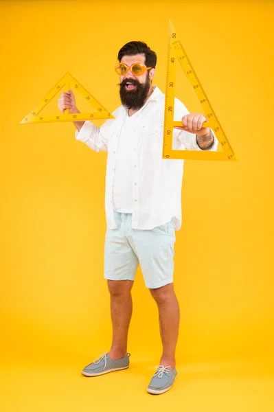 Ferramentas que você precisa para o seu desenho. Professor de Geometria ou Desenho Técnico. Homem barbudo segurando instrumentos de desenho no fundo amarelo. Engenheiro usando triângulos para fazer desenho de engenharia — Fotografia de Stock