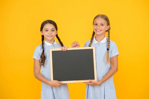 De vraies informations. Les petites filles tiennent surface d'écriture fond jaune. Enfants et tableau pour écrire des informations. Tableau blanc pour information. Espace de copie d'information scolaire frais. Nouvelles de l'école — Photo