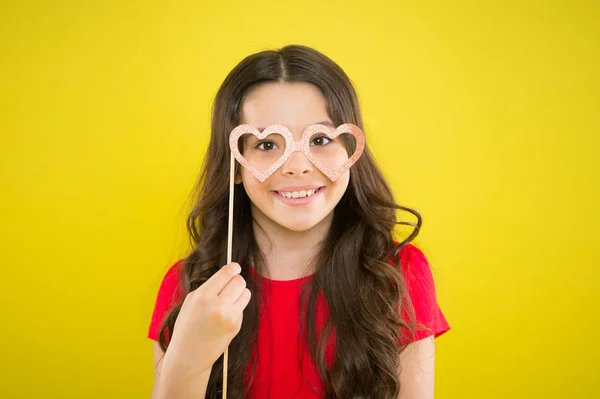 Fun time. happy girl on yellow background. summer fashion. small girl with party glasses. small girl hold funny glasses. happy birthday. party elements. child ready for party. prepare for party