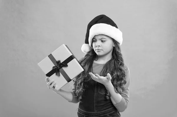 Present for Xmas. Childhood. New year party. Santa claus kid. Christmas shopping. Happy winter holidays. Small sad girl. Little girl child in santa hat. Wishing a happy New Year. waht is that — Stock Photo, Image