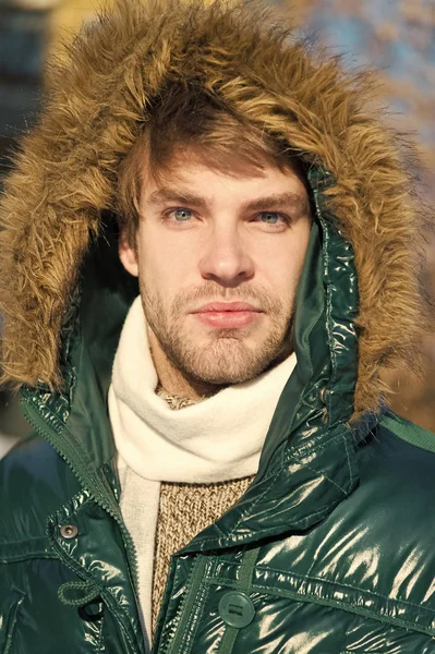 Winter stylish menswear. Winter outfit. Man unshaven wear warm jacket with fur snowy nature background. Guy wear winter jacket with furry hood. Hipster winter fashion. Prepared for weather changes