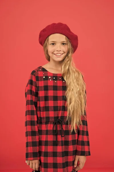Kid little cute girl with long hair posing in hat red background. Fashionable beret accessory for female. How to wear french beret. Beret style inspiration. How to wear beret like fashion girl