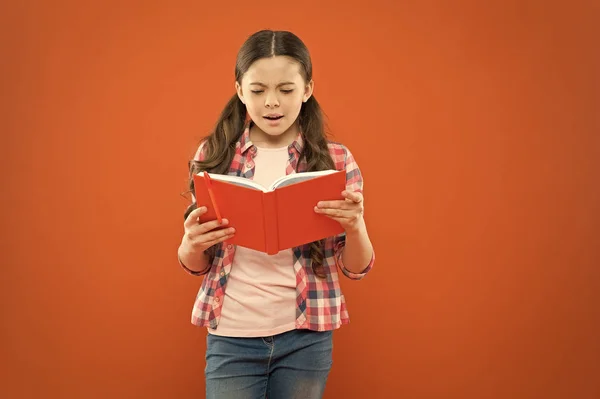 Es un verdadero ratón de biblioteca. Adorable libro de lectura infantil sobre fondo naranja. Linda niña leyendo por diversión. Desarrollar la capacidad de lectura en niños en edad escolar. Comprensión de lectura y fluidez — Foto de Stock