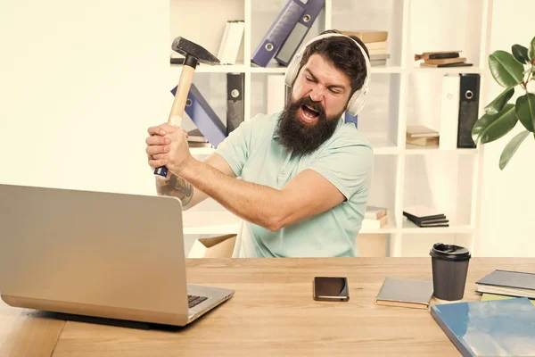 Outdated software. Computer lag. Reasons for computer lagging. How fix slow lagging system. Hate office routine. Man bearded guy headphones office swing hammer on computer. Slow internet connection