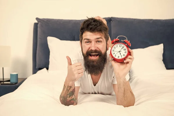 Profiter du temps libre à la maison. homme barbu heureux hipster avec réveil. homme endormi brutal dans la chambre. mâle avec barbe en pyjama sur le lit. endormi et réveillé. énergie et fatigue. gestion du temps — Photo