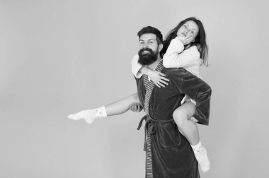Yakın ilişki. Yakışıklı genç adam kız arkadaşı piggyback binmek veren. Bornozçift eğlenceli turkuaz arka plan sahip. Evde kalıp eğlenelim. Her zaman birlikte eğlenirler.