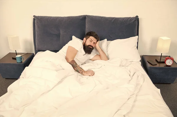 Uykusuzluk. Uyku bozuklukları kavramı. Adam sakallı hippi uyku ile ilgili sorunlar yaşıyorsanız. Yatakta yatan adam rahatla ve uykuya çalışın. Gevşeme teknikleri. Uyku ve uyanıklık ihlali — Stok fotoğraf
