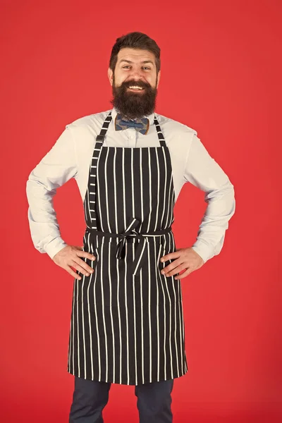 Je cuisinerai pour toi. Homme barbu cuisinier souriant dans le tablier. Maître cuisinier confiant avec barbe et moustache portant un tablier à bretelles. Chef cuisinier élégant en nœud papillon et tablier de cuisine — Photo