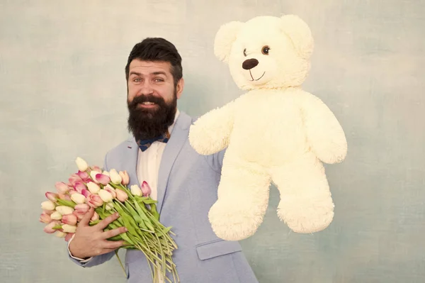 Sorpresa para ella. Hombre barbudo caballero traje pajarita agarre osito de peluche y ramo. Caballero haciendo una sorpresa romántica para ella. Un regalo romántico para caballeros. Saludos de cumpleaños. Feliz cumpleaños mi amor —  Fotos de Stock