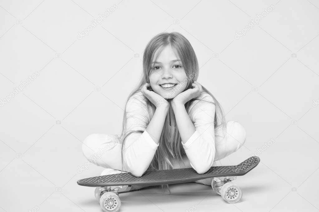 Enjoying life in the extreme speed. Happy small extreme athlete relaxing at violet penny board on pink background. Cute little child taking pleasure in extreme sport. Getting ready for some extreme