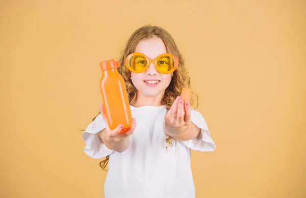 Βιταμίνη διατροφής. Μόδα παιδί γυαλιά ηλίου πίνουν αναζωογονητικό χυμό βιταμίνης. Υγειονομική περίθαλψη. Καλοκαιρινή δίαιτα βιταμινών. Καλή παιδική ηλικία. Φυσική πηγή βιταμινών. Κορίτσι τρώνε καρότο λαχανικών και πίνουν χυμό καρότο — Φωτογραφία Αρχείου