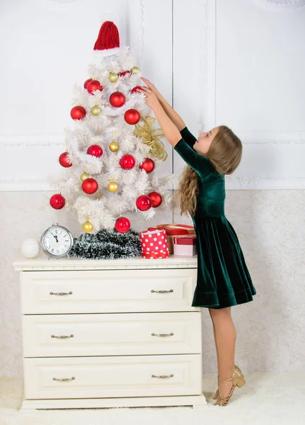 Dziewczyna świętować Boże Narodzenie. Najlepsze świąteczne pomysły dekorowanie pokoju dla dzieci. Dziecko powiesić Boże Narodzenie ornament piłkę na sztucznym drzewie. Dzieci mogą rozjaśnić choinkę, tworząc własne ozdoby — Zdjęcie stockowe