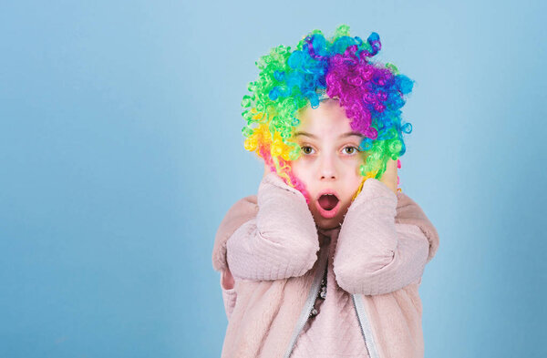 Wearing the foolish clown face. Surprised small clown with opened mouth. Adorable little girl wearing brightly colored clown hair wig. Everybody loves a clown, copy space