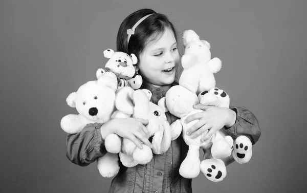 幸せな子供時代小さな女の子は柔らかいおもちゃのテディベアで遊びます。彼女の手にはたくさんのおもちゃがある。子供の頃のコンセプト。おもちゃの趣味を集める。子供の頃の思い出を大切に。おもちゃで笑顔の小さな女の子 — ストック写真
